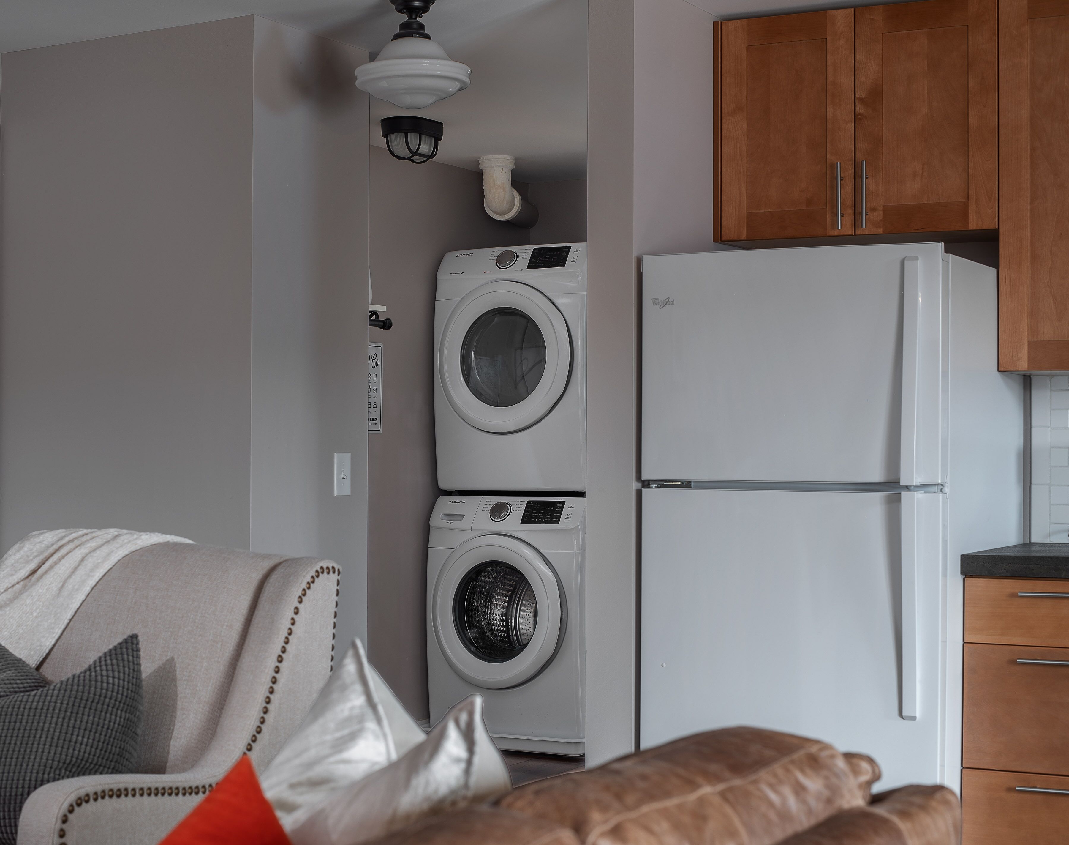 A compact kitchen with a white refrigerator, a washing machine, and wooden cabinets.