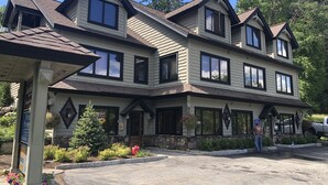 A two-story building with a symmetrical facade, large windows, and a stone foundation. - Lake view cozy two bedroom in Bolton Landing -  walk to Town! (Bolton)