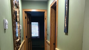 A hallway with wooden paneling, a patterned carpet, and a door leading to another room. - Lake view cozy two bedroom in Bolton Landing -  walk to Town! (Bolton)