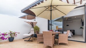 A patio with wicker furniture, a large umbrella, and a potted plant. - Healing Roof Terrace (Playa del Carmen)
