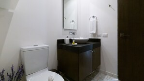 A bathroom with a toilet, sink, mirror, and dark wooden cabinet. - Healing Roof Terrace (Playa del Carmen)