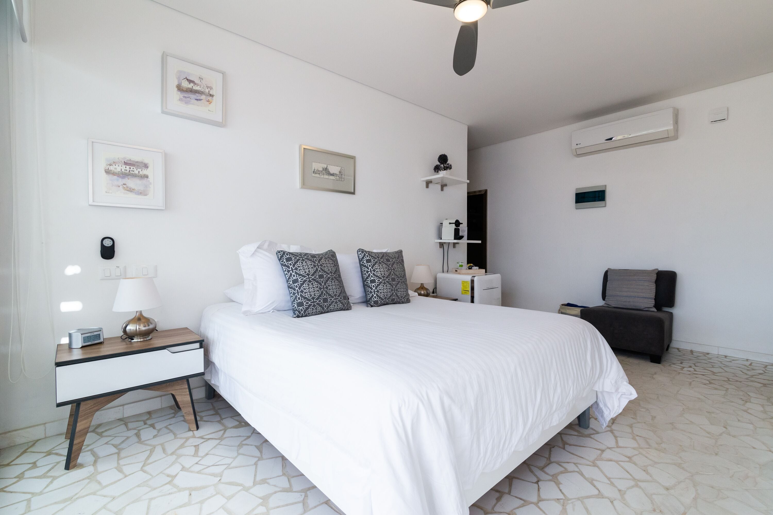 Un dormitorio con una cama, una mesita de noche, una silla y un ventilador de techo.