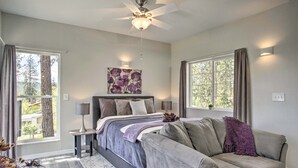 Een slaapkamer met een bed, een plafondventilator, een raam en een nachtkastje.