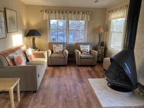 A cozy living room with a fireplace, two armchairs, a sofa, and a small table.