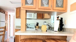 A kitchen with wooden cabinets, a white countertop, and two wooden stools. - Mountain Cabin,Jacuzzi,WIFI, Pets,10min Casino/Pets (Whittier)