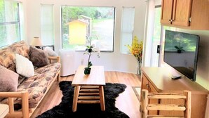 A modern living room with a sofa, a coffee table, a TV, and wooden cabinets. - Mountain Cabin,Jacuzzi,WIFI, Pets,10min Casino/Pets (Whittier)