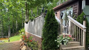 A wooden cabin with a wooden deck, a stone pathway, and a variety of plants and flowers. - Mountain Cabin,Jacuzzi,WIFI, Pets,10min Casino/Pets (Whittier)