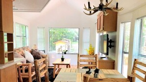 A cozy, rustic-style dining area with wooden furniture and a large window offering a view of the outdoors. - Mountain Cabin,Jacuzzi,WIFI, Pets,10min Casino/Pets (Whittier)