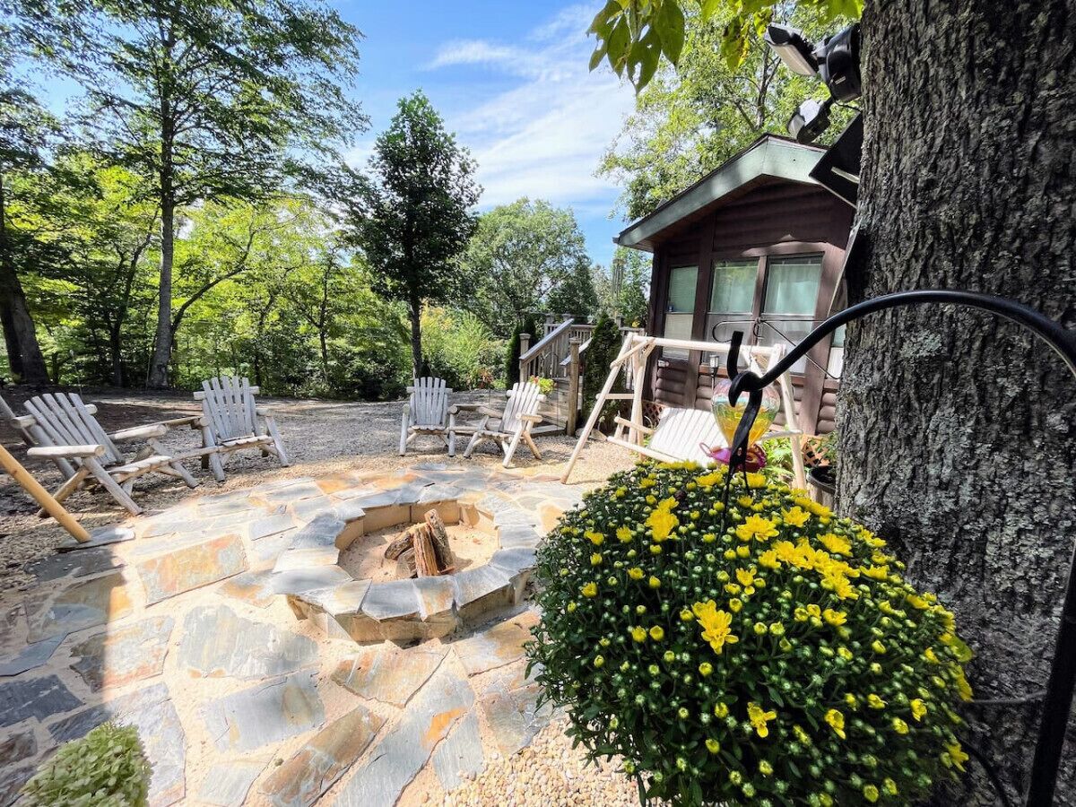 Une terrasse en pierre avec un foyer, des sièges d’extérieur et un chalet en bois.