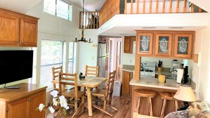 Una cocina amplia con armarios de madera, un comedor con mesa y sillas, y una escalera que conduce a un nivel superior.