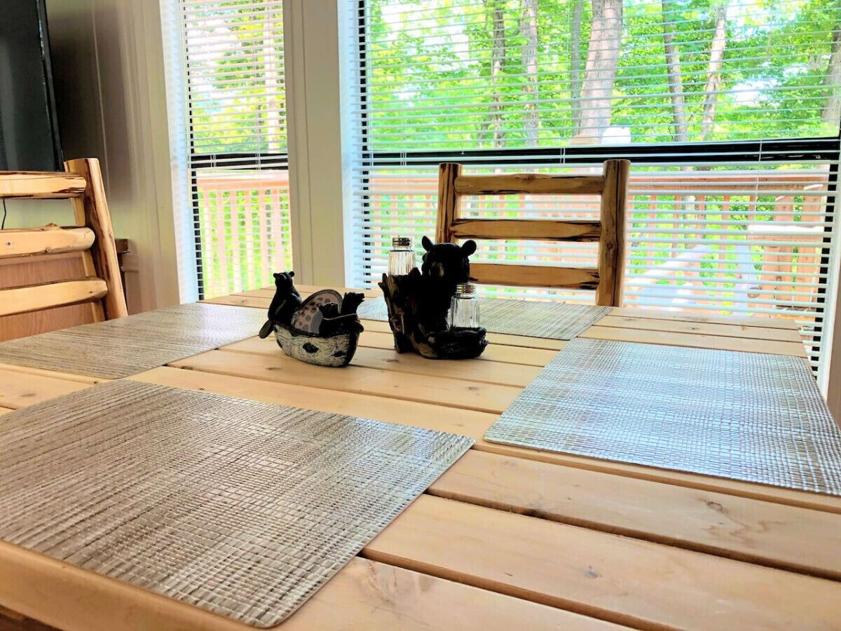 A wooden table with woven placemats and a decorative ceramic piggy bank.