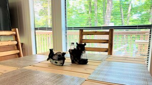 Une table en bois, agrémentée de sets de table en fibres tressées et d’une tirelire décorative en céramique en forme de cochon.