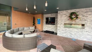 A modern outdoor seating area with a curved sofa, a small table, and a fireplace.