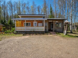 A two-story wooden cabin with a porch, a small attached shed, and a gravel driveway. - Vacation home Lokki by Interhome (Kouvola)