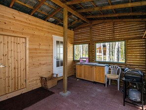 A wooden cabin interior with a kitchen area, a window with a view of trees, and a gas stove. - Vacation home Lokki by Interhome (Kouvola)