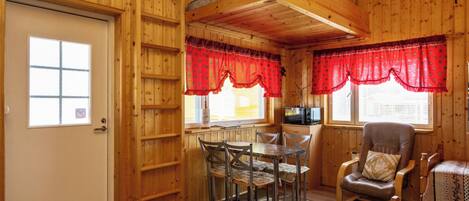 Interior de una cabaña de madera con comedor, cocina y zona de estar.