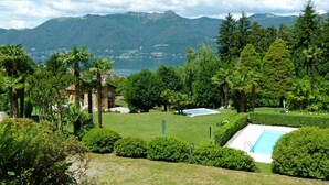 Un resort con piscina, exuberante vegetación y vistas a montañas y un lago.