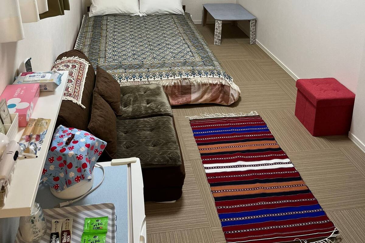 A compact bedroom with a bed, bedside table, and a small desk.
