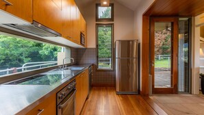 A modern kitchen with wooden cabinets, a stainless steel refrigerator, and a large window offering a view of the outdoors. - The Dairy @ Cavan, Kangaroo Valley, Stunning Views (Barrengarry)