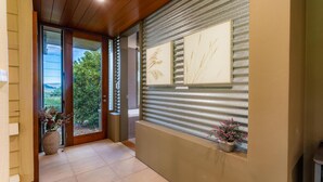 A modern entrance with a glass door, a view of greenery outside, and framed artwork on the wall. - The Dairy @ Cavan, Kangaroo Valley, Stunning Views (Barrengarry)