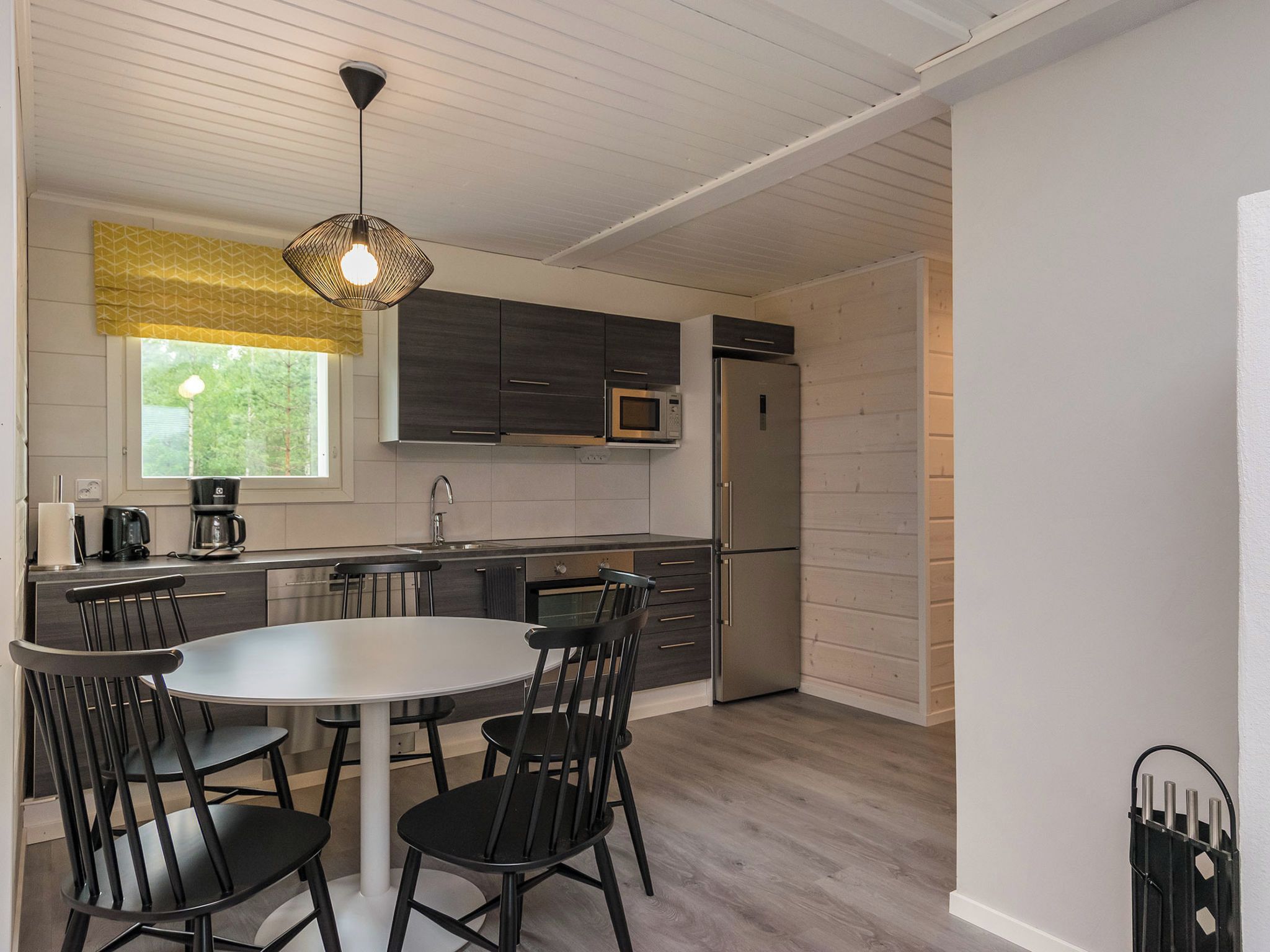A modern kitchen with a dining table and chairs, a microwave, and a refrigerator.