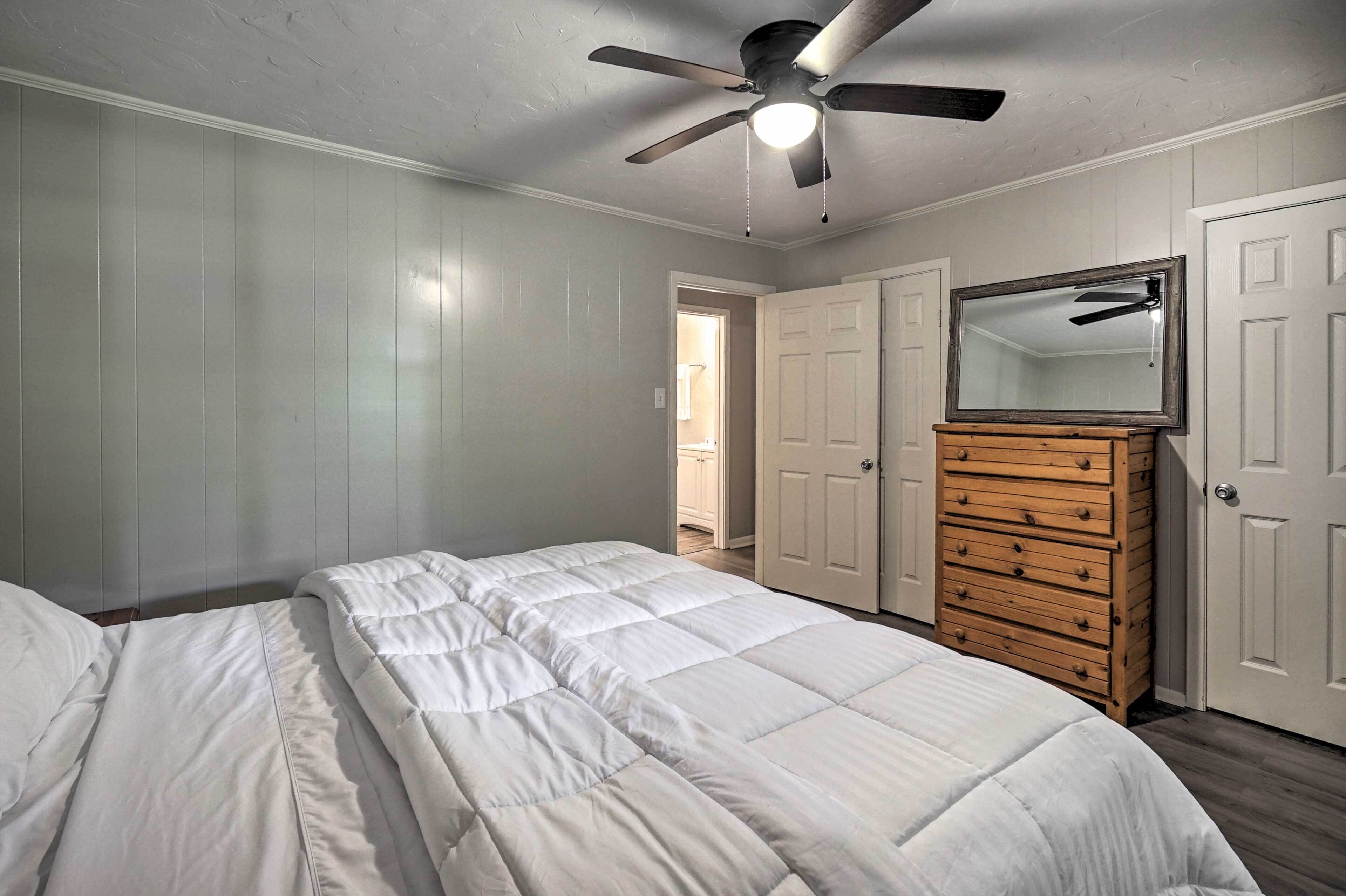 Une chambre à coucher avec un lit, une commode, un ventilateur de plafond et une porte.
