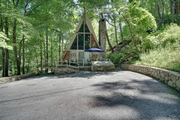 A cabin with a stone foundation, surrounded by a forest. - 'Snuggle Inn' in the Heart of Chalet Village! (Gatlinburg)