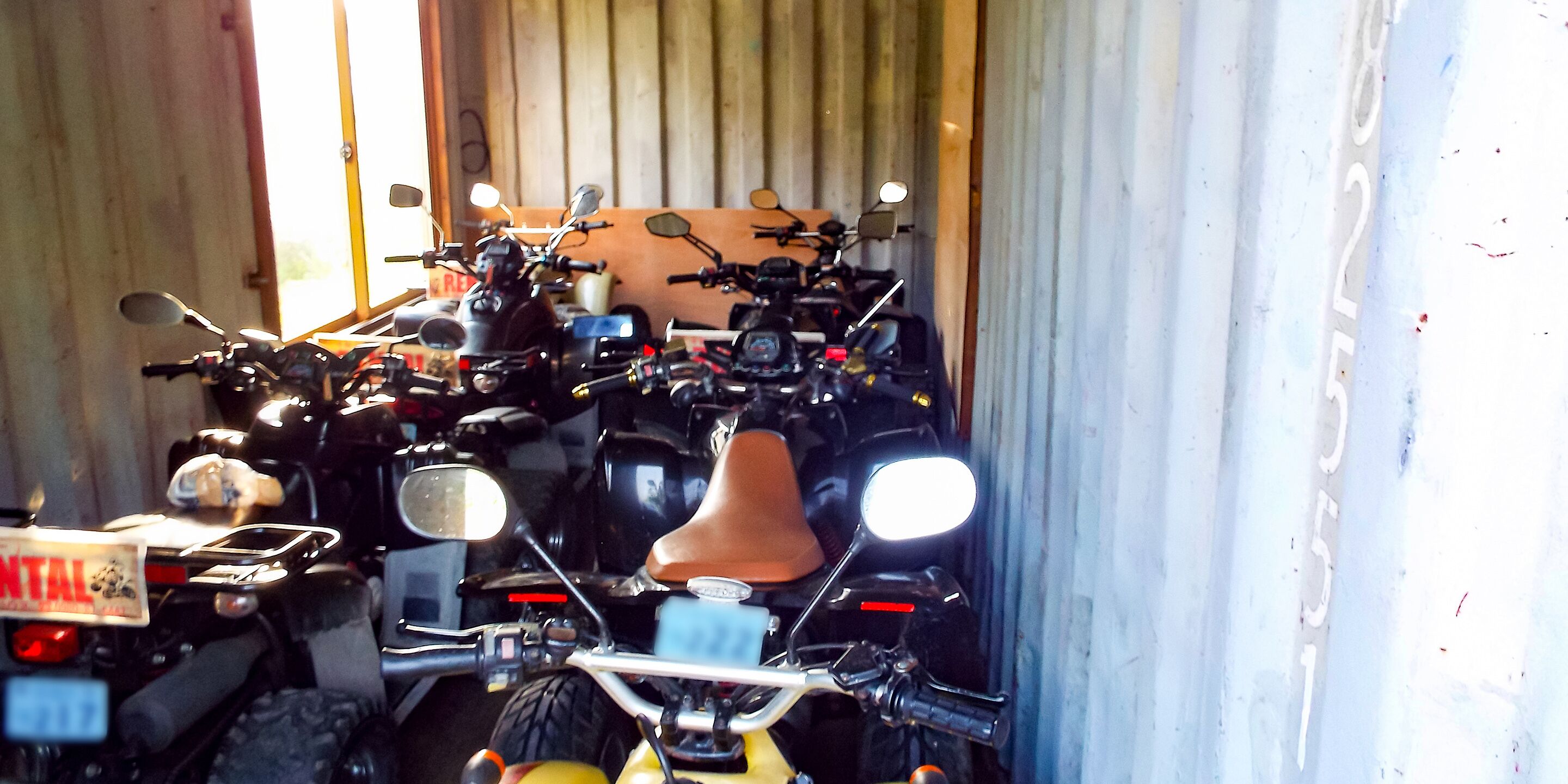 Een motorfiets geparkeerd in een gebouw met een houten deur en een metalen muur.
