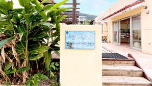 A building with a wooden pergola, a sign with Japanese characters, and a staircase leading to the entrance. - Asobi Base Yamabare House Ishigakijima (Ishigaki)