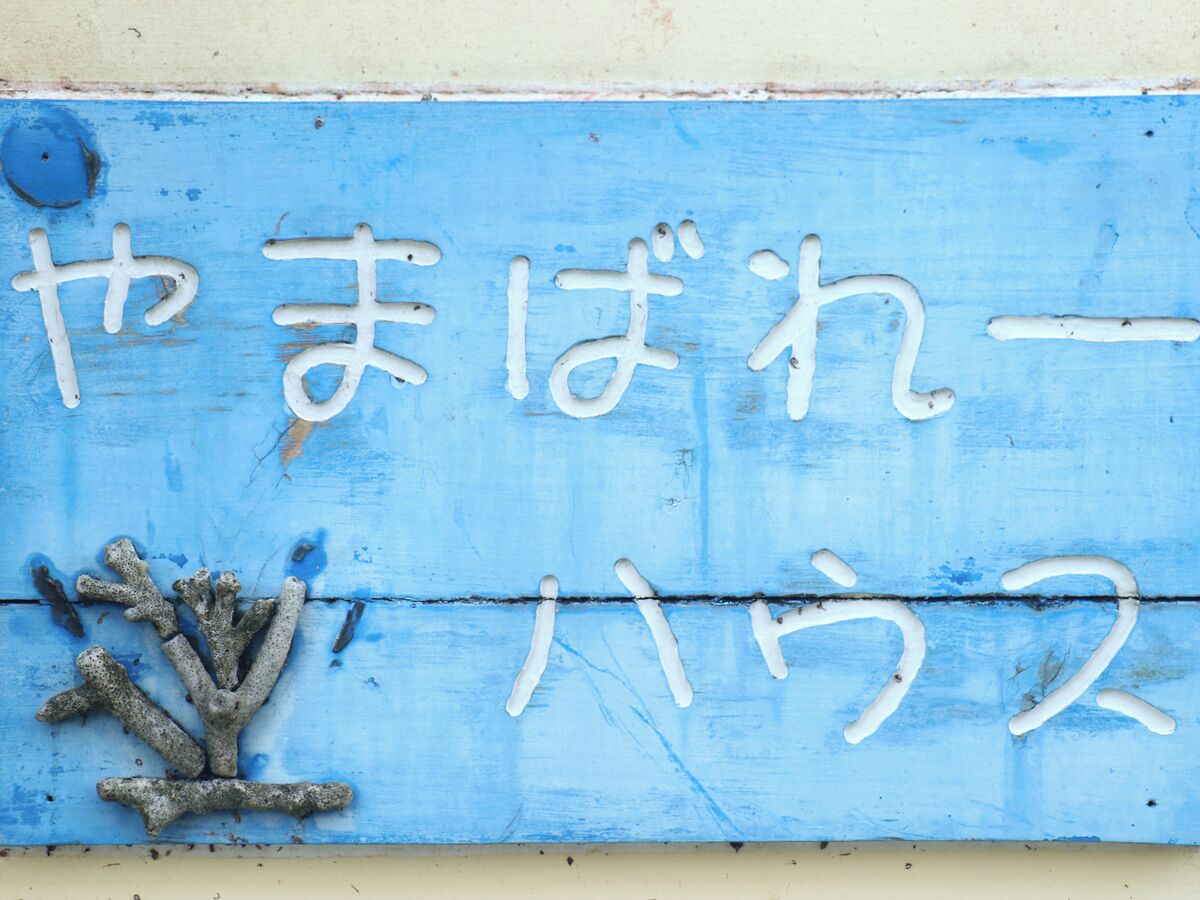 Un panneau bleu avec des caractères japonais blancs et un décor évoquant des coraux.
