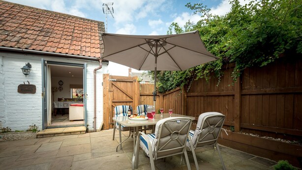 Une terrasse avec une table, des chaises et un grand parasol.