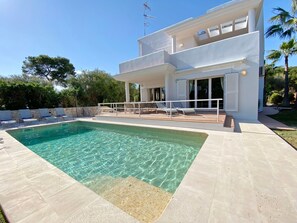 A modern two-story house with a swimming pool, outdoor seating, and a covered patio area.
