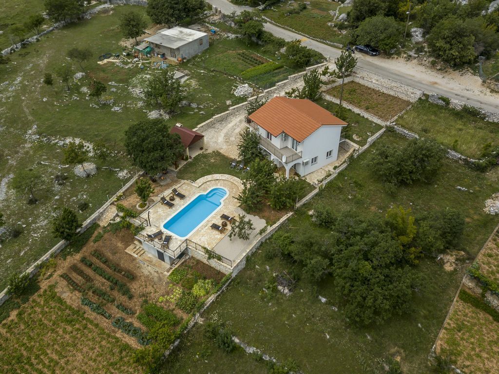 Ein Luftbild eines Wohnhauses mit Schwimmbad, einem zweistöckigen Haus und umliegenden Gärten.