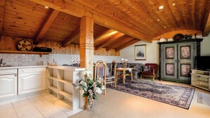 Une cuisine rustique avec des poutres en bois, un coin repas agrémenté d’un tapis et un buffet traditionnel orné d’œuvres d’art.