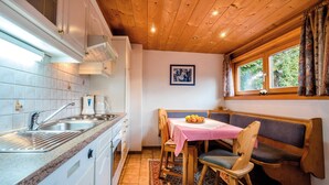 Une cuisine équipée d’un évier, d’une cuisinière et d’un coin repas avec une table et des chaises.