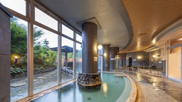 An indoor swimming pool with stone pillars and large windows. - Kamenoi Hotel Aso (Aso)