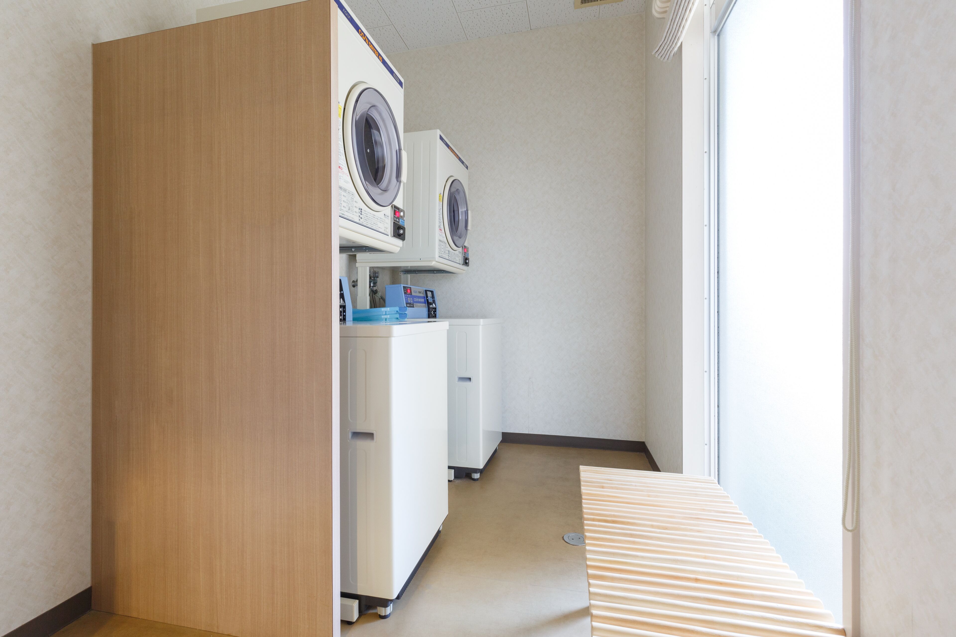 A laundry room with two washing machines, a dryer, and a small table.