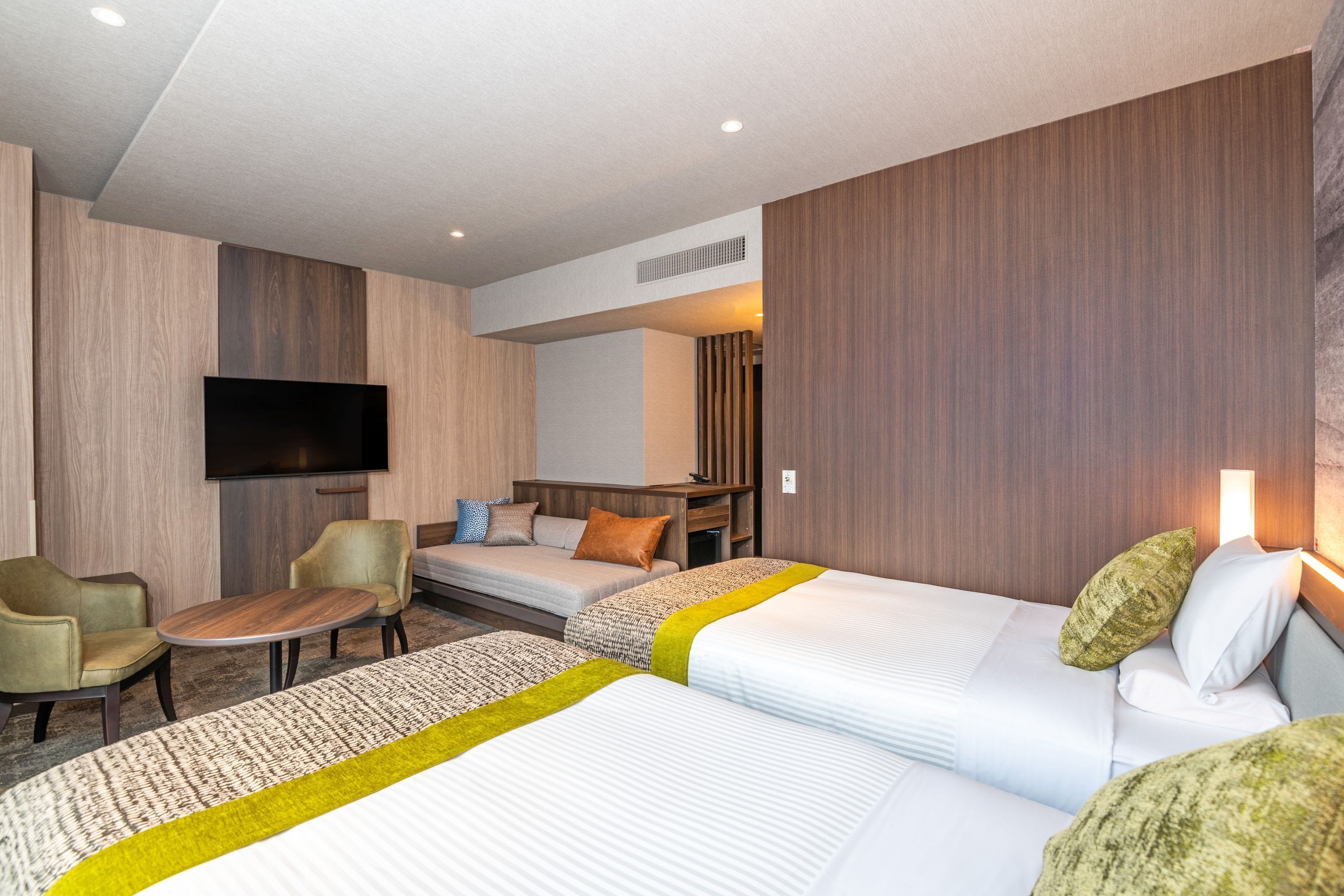 Una habitación de hotel con dos camas, televisión, escritorio y una silla.