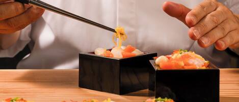 A person using chopsticks to pick up food from a black box.