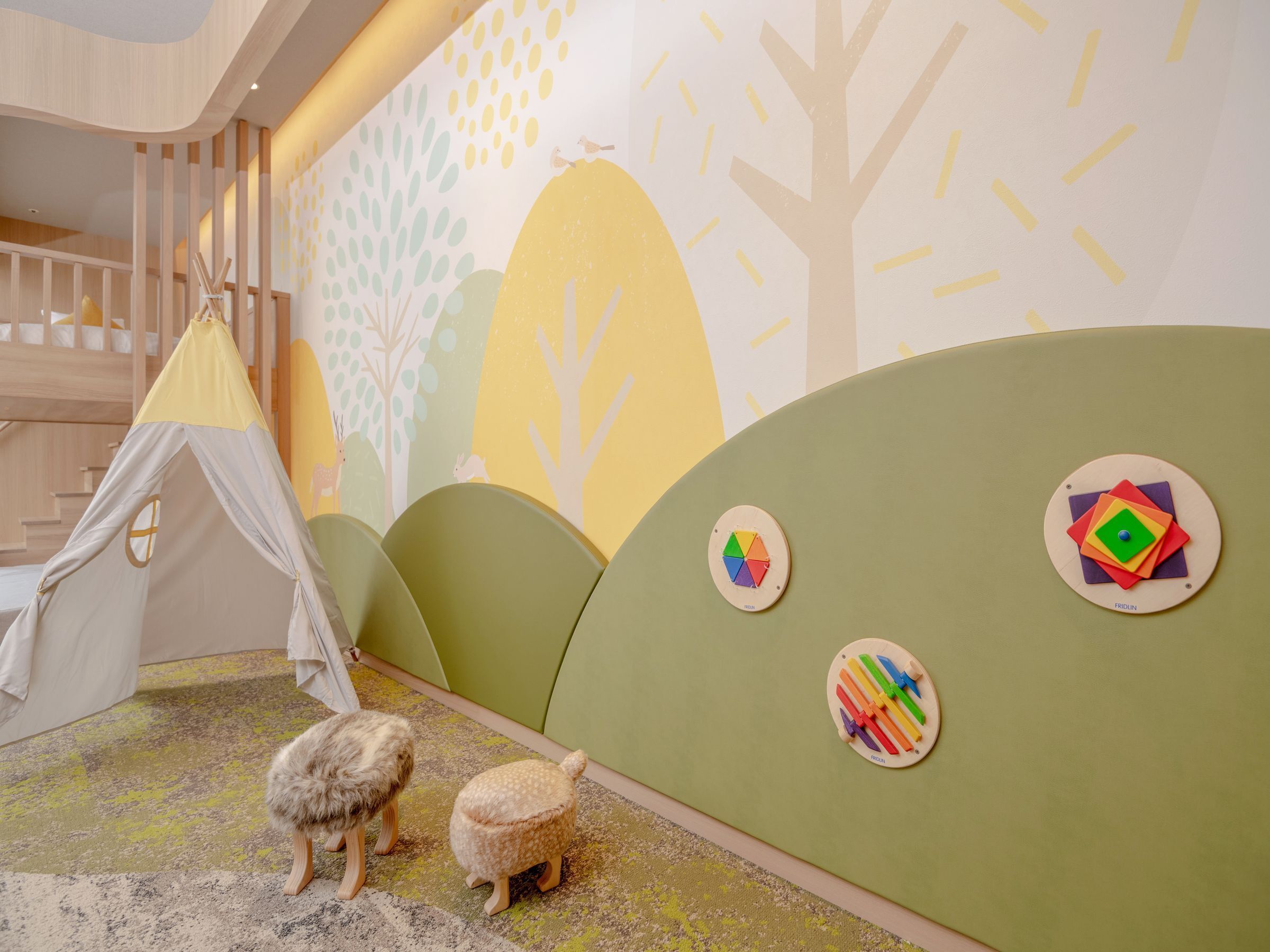 A children's play area with a tent, two plush toys, and wall decorations.