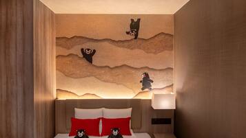 A hotel room with a bed, pillows, a nightstand, and a wall with bear-themed artwork.