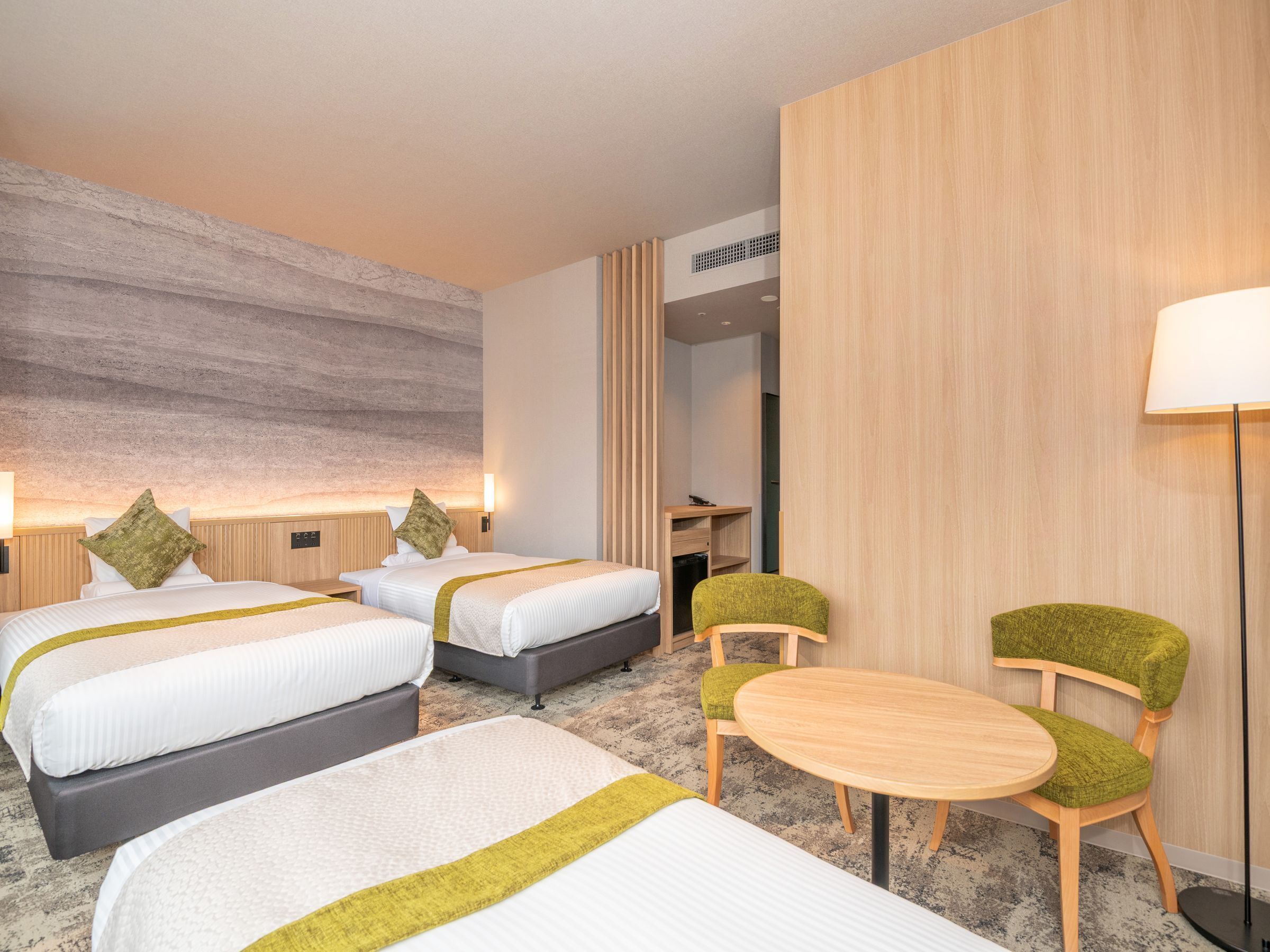 A hotel room with two beds, a desk, and a chair.