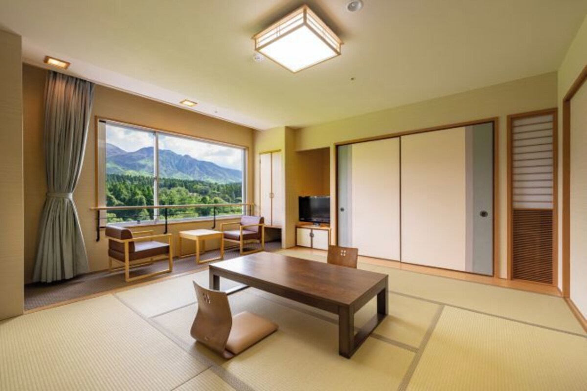 A traditional Japanese-style room with tatami flooring, a low wooden table, and a television on a stand.