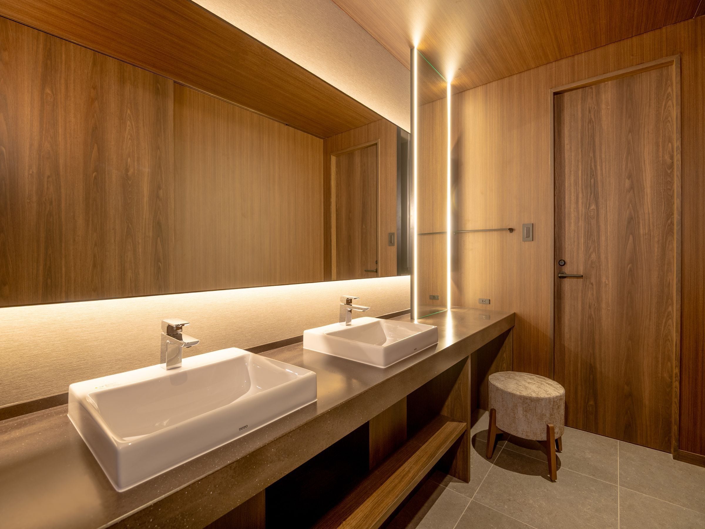 Ein modernes Badezimmer mit zwei Waschbecken, einem großen Spiegel und einer Holzkommode.