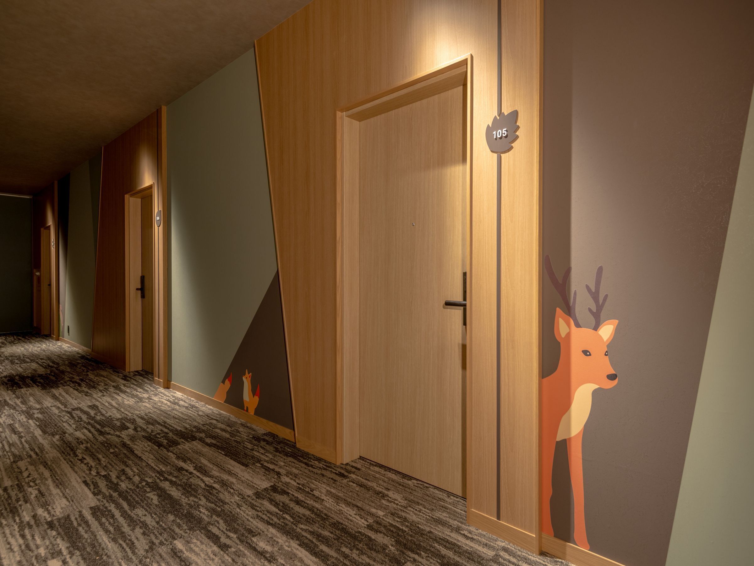 A hotel corridor with wooden doors, a carpeted floor, and a wall mural of a deer.