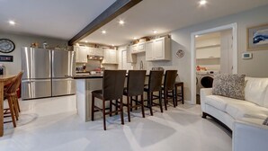 A modern kitchen with white cabinets, a stainless steel refrigerator, and a dining area with wooden chairs. - 4 Master Suites in the Heart of Alaska...Abby's Place..... (Palmer)