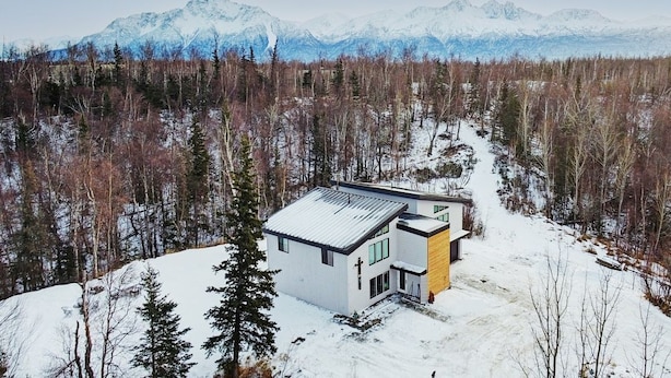 A modern two-story house with a metal roof, surrounded by a snowy forest and mountains in the background. - 4 Master Suites in the Heart of Alaska...Abby's Place..... (Palmer)