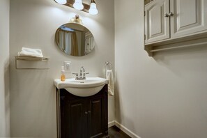 A bathroom with a white sink, dark cabinets, a round mirror, and a towel rack. - 4 Master Suites in the Heart of Alaska...Abby's Place..... (Palmer)