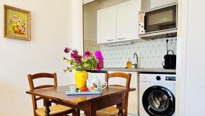 Une cuisine équipée d’une table à manger, de chaises, d’un lave-linge et d’un four à micro-ondes.