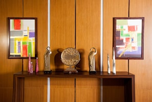A wooden reception desk with three framed artworks and two decorative vases.